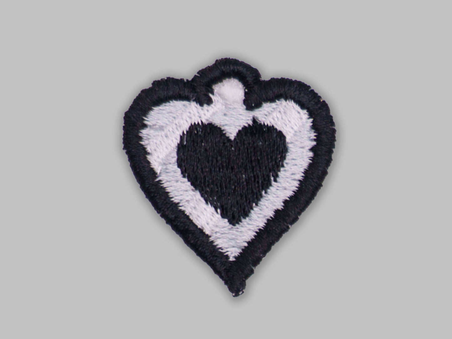 Heart-shaped patch with black and white design on a gray background