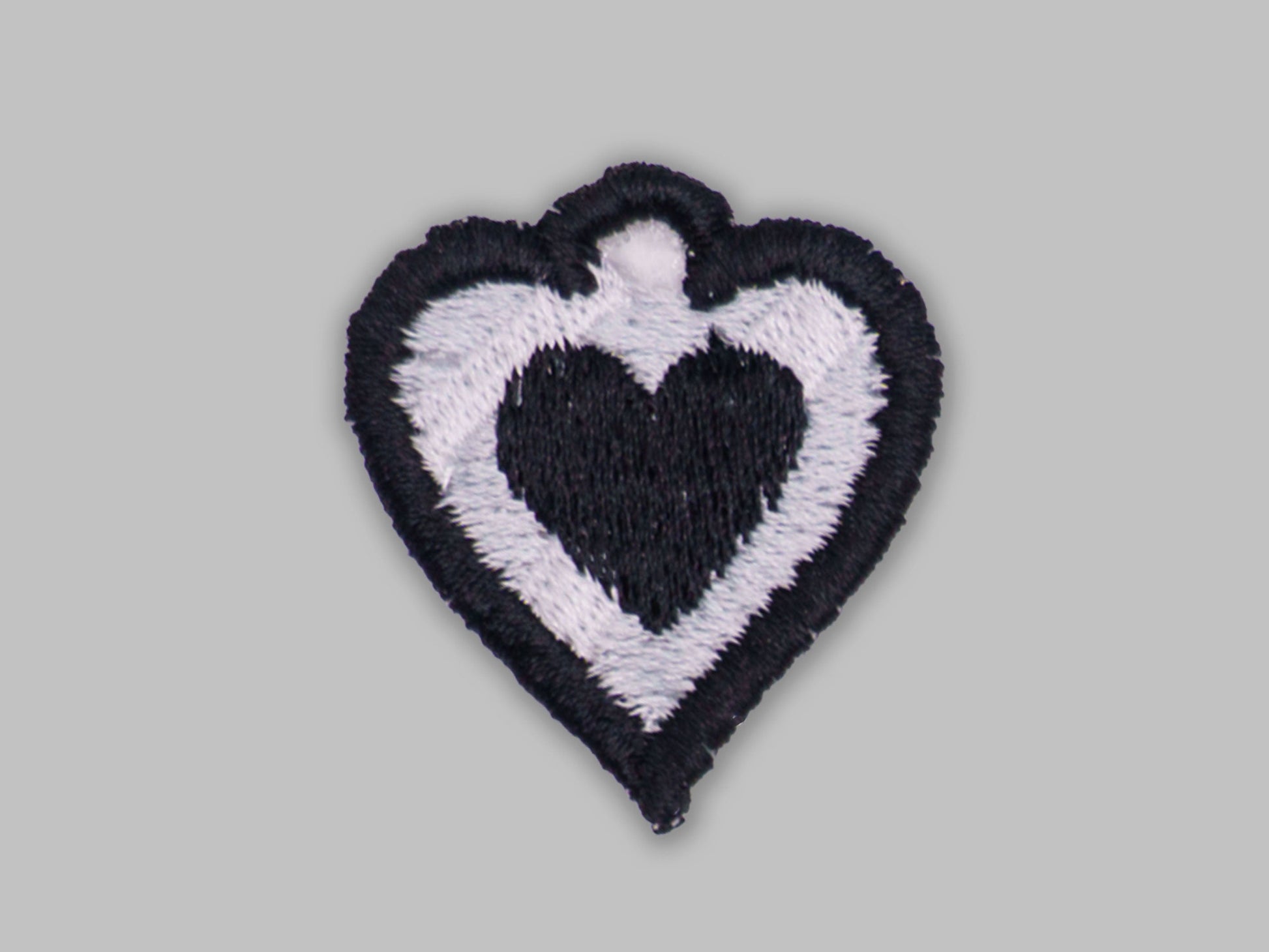 Heart-shaped patch with black and white design on a gray background