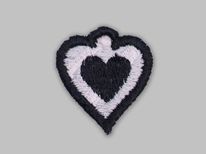 Heart-shaped patch with black and white design on a gray background