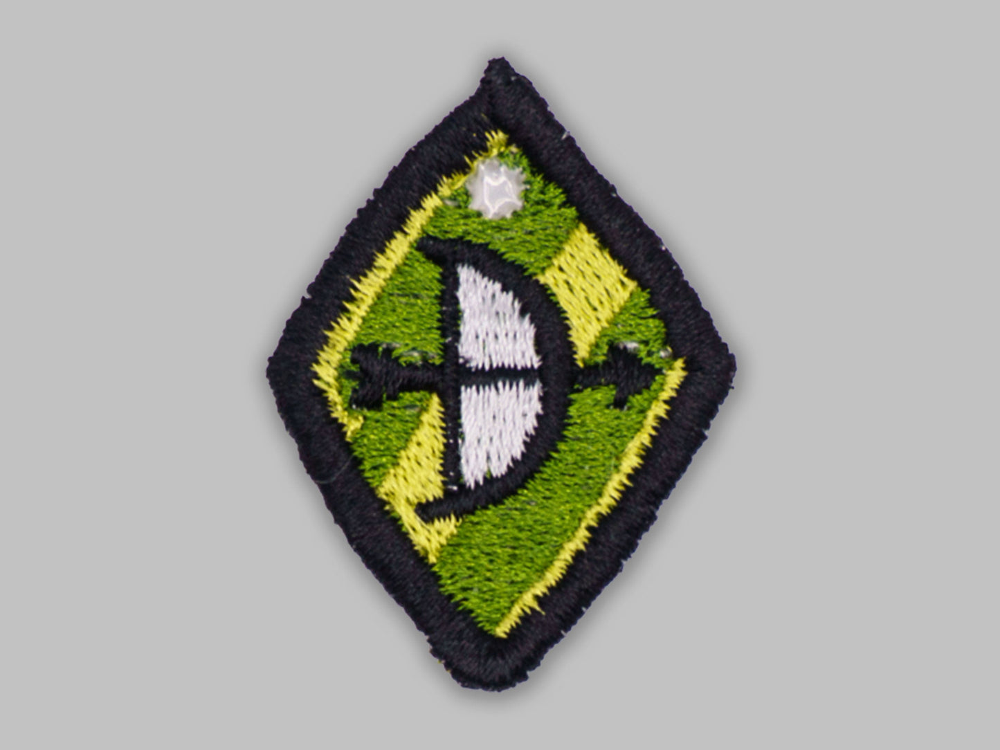 Embroidered patch with a green and yellow diamond shape on a gray background