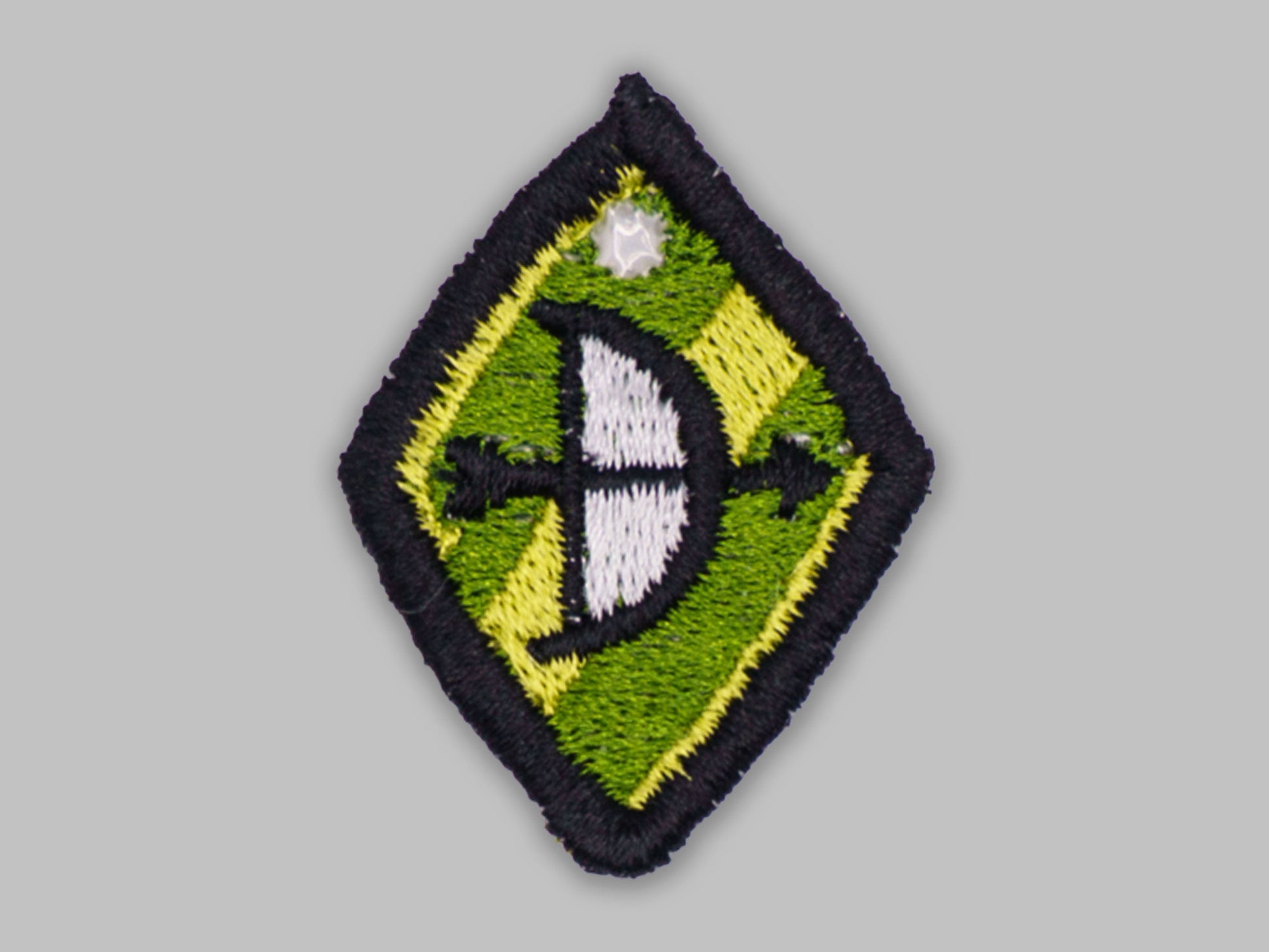 Embroidered patch with a green and yellow diamond shape on a gray background