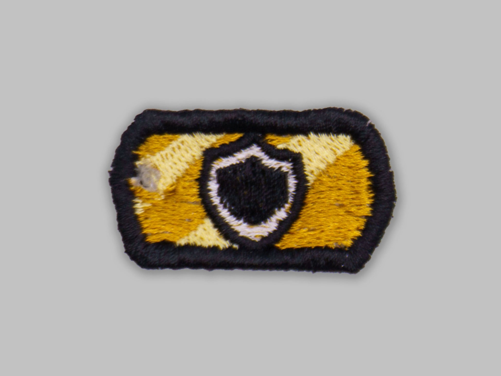 Embroidered patch with a shield design on a gray background