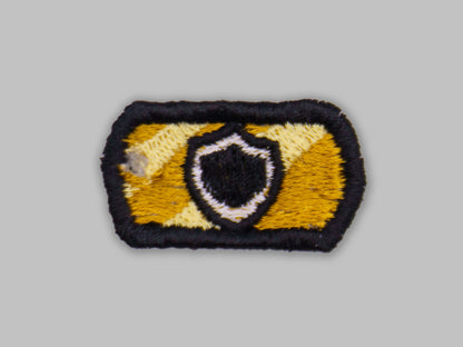 Embroidered patch with a shield design on a gray background